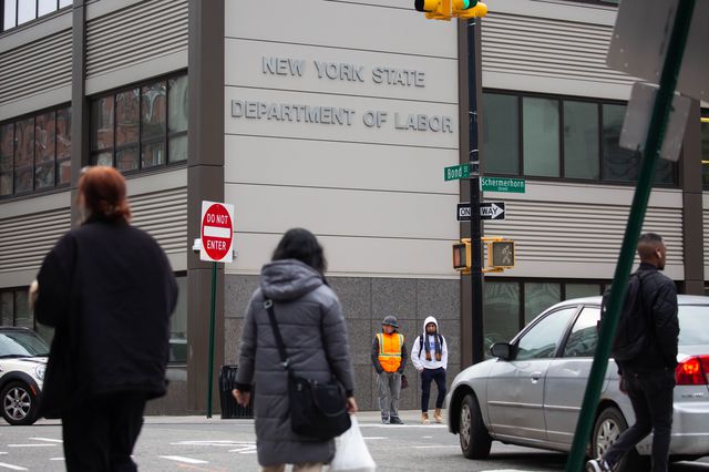 Pedestrians in front of a New York State Department of Labor building in a photograph taken across the street.